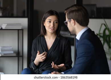Concentrated millennial indian female candidate on vacant place answering question of male hr introducing herself on job interview, attentive man client listening to mixed race woman expert consultant