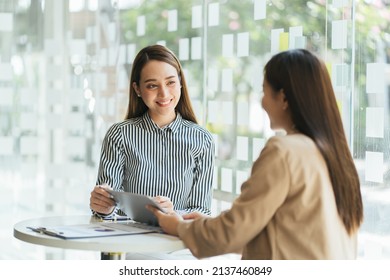 Concentrated multiethnic female employees sit at desk in office work together using computer. Focused women colleagues coworkers cooperate on laptop, brainstorm discuss business ideas at meeting. - Shutterstock ID 2137460849