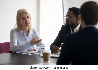 Concentrated multiracial businesspeople sit in boardroom brainstorm considering business project together, focused diverse multiethnic colleagues partners talk discuss ideas, cooperating at meeting - Shutterstock ID 1666851532