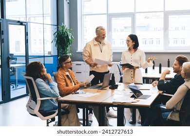 Concentrated multiracial colleagues in casual clothes having meeting and discussing ideas while working together in modern office during conference process - Powered by Shutterstock