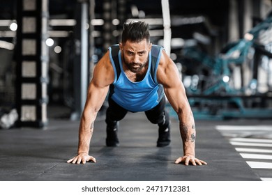 Concentrated muscular guy training in gym, doing push up exercises, free space - Powered by Shutterstock