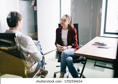 Concentrated Office Employees Having Conversation On Work Related Topics While Sitting Behind Glass In Modern Empty Office Room With Wooden Table