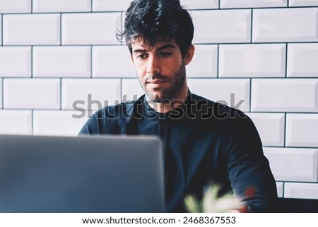 Concentrated it professional working on developing new programme via free high speed internet connection on laptop computer.Male graphic designer creating own website on modern netbook device