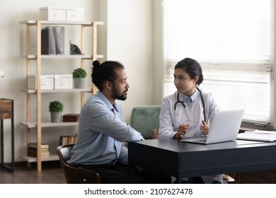 Concentrated skilled young Indian general practitioner doctor explaining test results or illness treatment protocol on computer to African American male patient, medical insurance, healthcare concept.