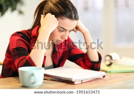 Concentrated student studying memorizing notes sitting in a table at home