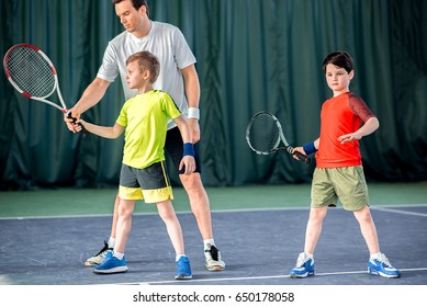 Concentrated Tennis Player Teaching Kids On Court