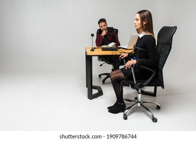 Concentrated, Thoughtful Woman Is In A Bright Room, Testing On A Computer Polygraph. Young Man Sitting At The Table And Looking At The Polygraph Screen And Polygraph Monitoring. The Concept Of Truth, 