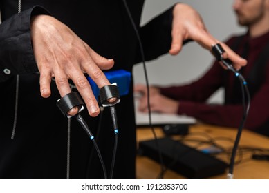 Concentrated, Thoughtful Woman Is In A Bright Room, Testing On A Computer Polygraph. Young Man Sitting At The Table And Looking At The Polygraph Screen And Polygraph Monitoring. The Concept Of Truth