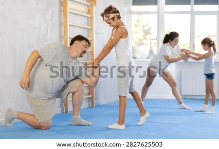 Concentrated tween boy practicing basic protection skills in training bout with father during family self defense course in gym ..