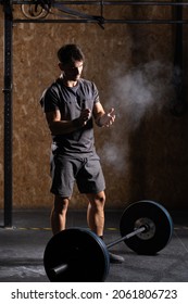 Concentrated Weightlifter Clapping Hands With Chalk Before Lifting A Heavy Barbell.