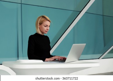 Concentrated Woman Developer Performs Software Engineering On Net-book While Sitting In Office Interior, Young Businesswoman Searching Information In Internet Via Laptop Computer During Work Break 