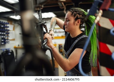 Concentrated Woman Fixing Bike Wheel In Workshop