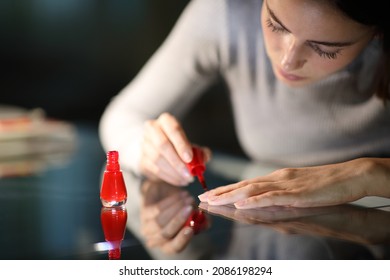 Concentrated Woman Painting Nails In Red At Home In The Night