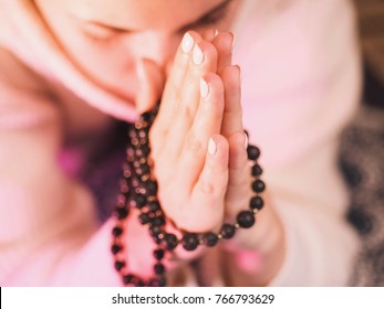 Concentrated woman praying wearing rosary beads. Namaste. Close up hands. - Powered by Shutterstock