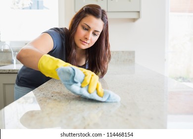 Concentrated woman scrubbing the bar in kitchen