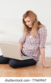 Konzentrierte Frau, die auf ihrem Laptop surft und im Wohnzimmer sitzt. Arbeiten von zu Hause aus in Quarantänesperrung. soziale Distanzierung der Selbstisolierung