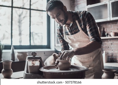 Concentrated at work. Confident young man making ceramic pot on the pottery wheel - Powered by Shutterstock