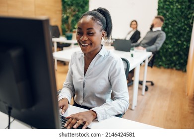 Concentrated Young African American Business Woman Working On A Laptop While Sitting At The Table In The Office. Confident Business Expert. E-commerce, Internet Technology Or Small Business Concept.