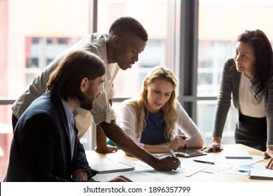 Concentrated young african american employee analyzing marketing research results or sales statistics data at briefing meeting with motivated older korean and young caucasian colleagues in office. - Shutterstock ID 1896357799