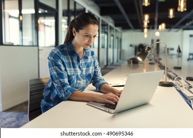 Concentrated young casual freelancer business woman working on computer in modern open space startup - Shutterstock ID 490695346