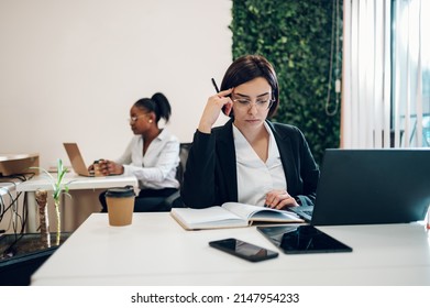 Concentrated Young Caucasian Business Woman Working On A Laptop While Sitting At The Table In The Office. Confident Business Expert. E-commerce, Internet Technology Or Small Business Concept.