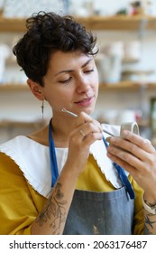 Concentrated Young Ceramist Using Scraper For Shaping Pottery Tableware During Ceramic Manufacturing Lesson Or Class In Workshop. Happy Craftswoman Work In Studio For Small Business Entrepreneurship