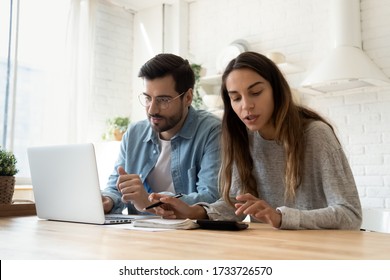 Konzentriertes junges Paar sitzt am Schreibtisch in der Küche bezahlen Rechnungen auf Computer online berechnen Finanzen zusammen, tausendjährige Ehemann und Ehefrau verwalten Haushaltsausgaben verwenden Internet-Banking-System auf Laptop