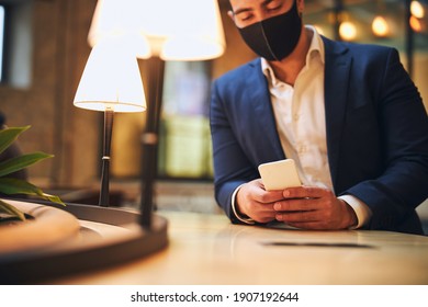 Concentrated Young Dark-haired Male In A Face Covering Writing A Text Message On His Cellphone