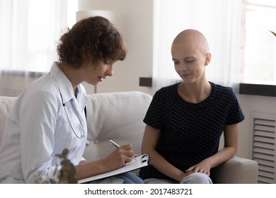 Concentrated Young Female Doctor Oncologist Handwriting Prescription Or Disease Treatment To Smiling Millennial Hairless After Chemotherapy Woman With Cancer, Doing Regular Checkup, Healthcare Concept