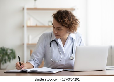 Concentrated young female general practitioner physician writing notes in registry book, working in clinic office. Skilled professional doctor prescribing disease treatment, involved in paperwork. - Powered by Shutterstock