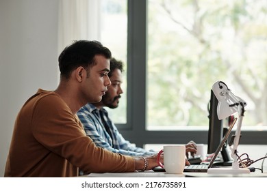 Concentrated Young Indian Software Engineer Working On Laptop At His Office Desk