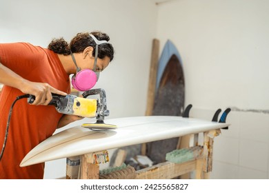 Concentrated young latin man repairing and polishing a surfboard in a workshop - Powered by Shutterstock