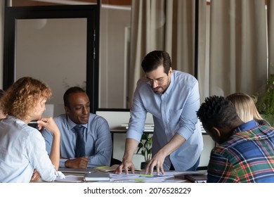 Concentrated Young Male Ceo Executive Manager Leader Analyzing Paper Documents Or Marketing Research Results With Motivated Multiethnic Colleagues At Brainstorming Meeting In Modern Office Room.