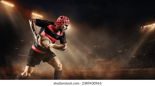 Concentrated young man, rugby player in uniform with ball standing on dark empty field with flashlights and mist. Game on. Concept of professional sport, competition, motivation, game, championship - Powered by Shutterstock