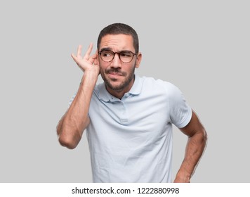 Concentrated Young Man Trying To Listen With His Hand