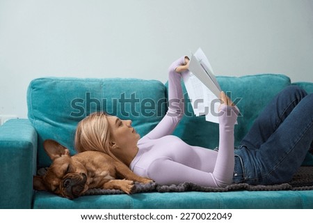 Concentrated young woman reading documents on sofa