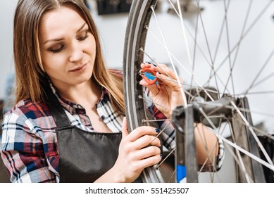 Concentrated young woman repairing the bicycle in the garage - Powered by Shutterstock