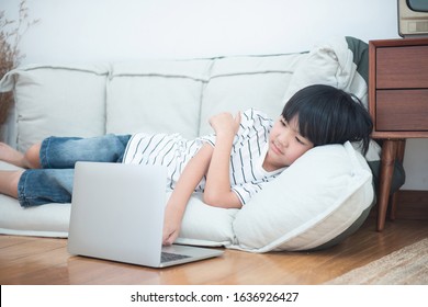 Concentration Asian Child Kid Playing Game In Laptop Computer Lying On Sofa In Home,happy Student Using Internet After School. 