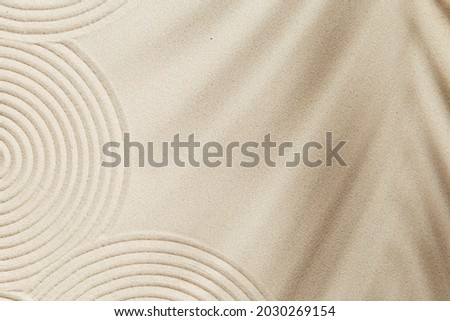 Concentration and spirituality in Japanese zen garden,  lines drawing in sand and shadows of palm leaves. Spa background, concept for meditation and relaxation. View from above.