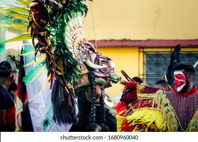 Concepcion De La Vega, DOMINICAN REPUBLIC - FEBRUARY 09, 2020: Strong Man Carries Native Indian Mask Passing By City Street At Dominican Carnival On February 9 In Concepcion De La Vega