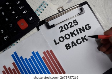 Concept of 2025 looking back write on clipboard isolated on Wooden Table.