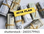 Concept of 401K Plan write on sticky and dollars notes isolated on Wooden Table.