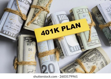 Concept of 401K Plan write on sticky and dollars notes isolated on Wooden Table.