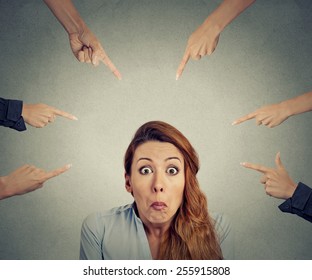 Concept of accusation of guilty businesswoman. Portrait confused upset woman many fingers pointing at her isolated on grey office background. Human face expression negative emotion feeling