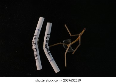 The concept of addiction in smoking, smokers want to quit smoking. Image of a character made of cigarettes, it says illegal cigarettes on a black background. Cigarette butts on a black background.