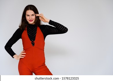 Concept adult girl on a white background. A photo of a pretty brunette girl in red trousers and a black sweater smiles and shows different emotions in different poses right in front of the camera. - Shutterstock ID 1578123325
