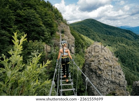 Concept: adventure. Woman with helmet, harness. Walking on a bridge. Doing via ferrata. Via ferrata in Skalka, kremnica, Slovakia. 