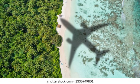 Concept of airplane travel to exotic destination with shadow of commercial airplane flying above beautiful tropical beach. Beach holidays and travel. - Powered by Shutterstock