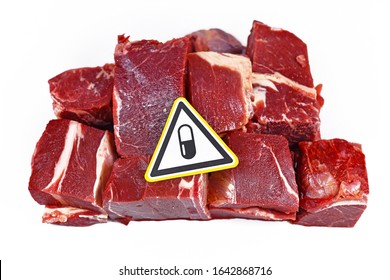 Concept For Antibiotics Residue And Harmful Bacteria In Meat For Human Consumption, Showing Chunks Of Red Meat With Yellow Warning Sign With Pill