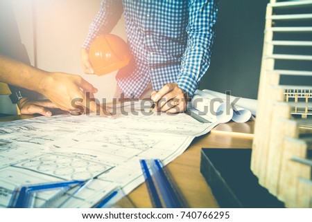 Concept architects, Two asian engineer pointing equipment architects On the desk with a blueprint in the office, Vintage, Sunset light.Selective Focus